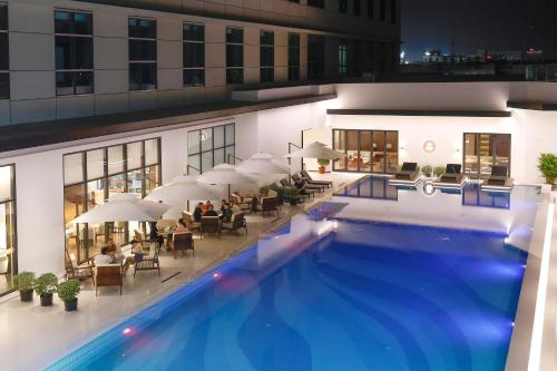 a hotel with a large swimming pool with people sitting at VM Hotel in Phnom Penh