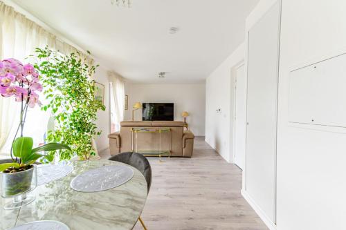 une salle à manger avec une table en verre et des fleurs dans l'établissement Appartement Palaric - Welkeys, à Saint-Ouen