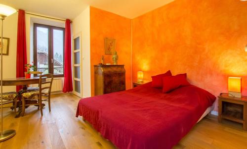 a bedroom with a red bed and a table at Gite des Sources d'Arvey in Verrens-Arvey