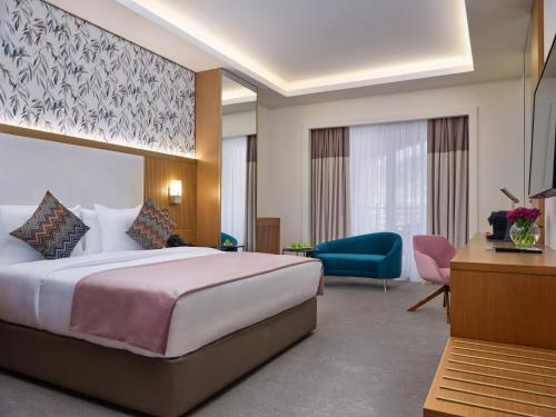um quarto de hotel com uma cama e uma cadeira azul em Qafqaz Riverside Hotel em Gabala