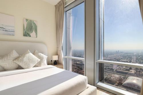 a bedroom with a white bed and a large window at Visionary Vista: 2BR Al Habtoor City in Dubai