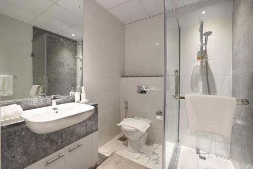 a bathroom with a sink and a toilet and a shower at Visionary Vista: 2BR Al Habtoor City in Dubai