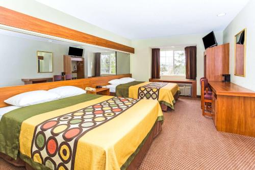 a hotel room with two beds and a desk at Super 8 by Wyndham Parker/SE Denver Area in Parker