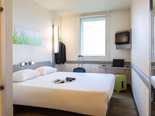 um quarto de hotel com uma cama branca e uma janela em ibis budget Roissy CDG Paris Nord 2 em Roissy