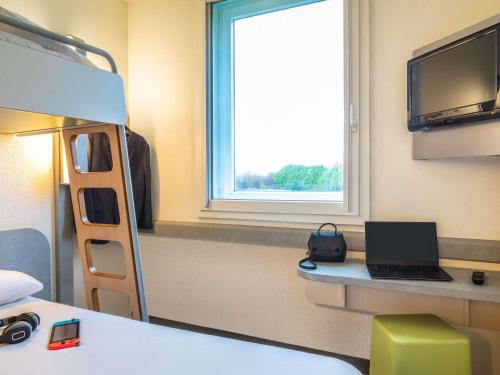 a room with a bunk bed with a laptop on a desk at ibis budget Roissy CDG Paris Nord 2 in Roissy-en-France