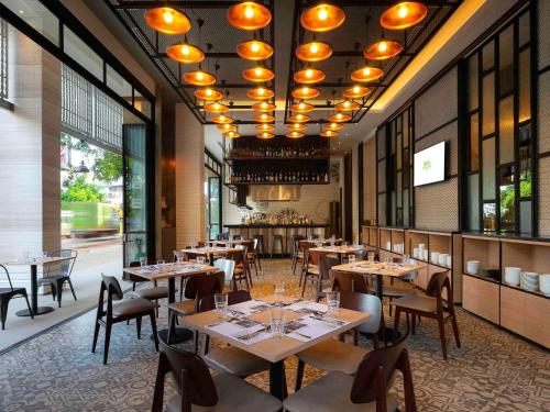 um restaurante com mesas e cadeiras de madeira e janelas em ibis Styles Siem Reap em Siem Reap