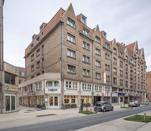 un grand bâtiment en briques au coin d'une rue dans l'établissement Best Western Plus Hotel Cargo, à Dunkerque