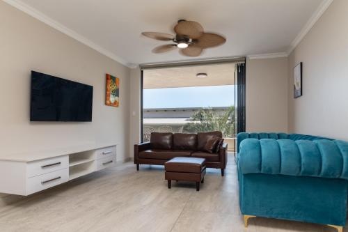 a living room with a blue couch and a tv at Shanthi Apartment 2 in Ballito