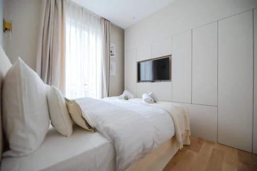 - une chambre blanche avec un grand lit et une télévision dans l'établissement Luxury Flat - Opera & Upper Marais, à Paris
