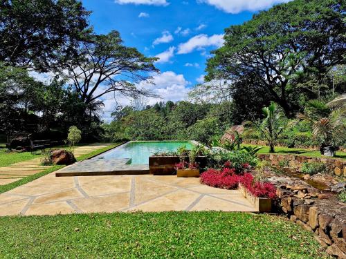 une piscine dans un jardin avec un mur en pierre dans l'établissement GlenMyu Estate, à Haputale