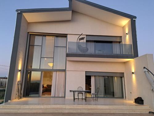 een huis met een balkon met een tafel bij Villa Deluxe Au Pied de l'Atlas in Ksar et Tlatia