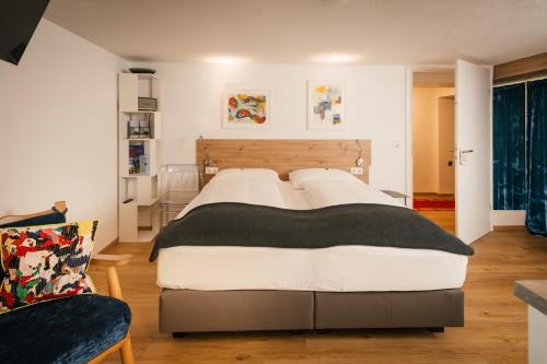 ein Schlafzimmer mit einem großen Bett und einem Stuhl in der Unterkunft Villa Marwa - eine Ruheoase im Grünen in Innsbruck