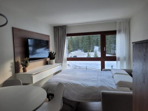 een slaapkamer met een groot bed en een groot raam bij SWEET Alps Apartment CCM in Madonna di Campiglio