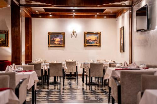 a dining room with white tables and chairs at Hôtel L'Hacienda in Rabat