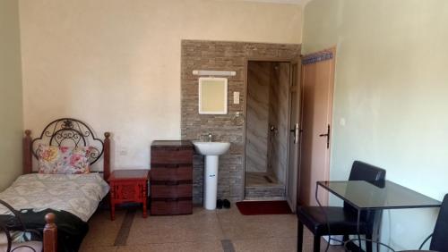 a bedroom with a bed and a sink and a bathroom at hôtel hicham in Ouarzazate