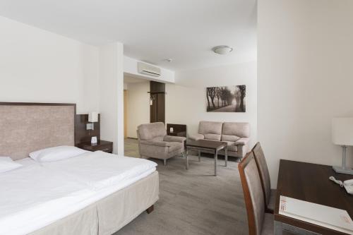 een hotelkamer met een bed, een bureau en stoelen bij Hotel Orange Przeźmierowo in Przeźmierowo