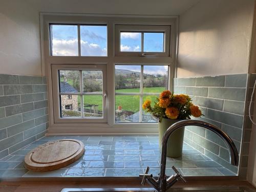 een badkamer met een raam en een wastafel met een vaas met bloemen bij Wonderfully Scenic and Comfortable Dales Mill Property in West Burton