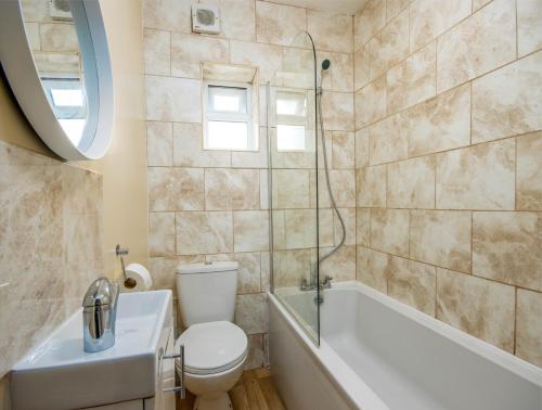 La salle de bains est pourvue de toilettes, d'une baignoire et d'un lavabo. dans l'établissement 4 Bed House With Driveway Parking, à Southampton