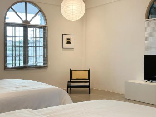 Schlafzimmer mit einem Bett, einem TV und einem Stuhl in der Unterkunft Heritage Vacation Inn Balcony in Kuching