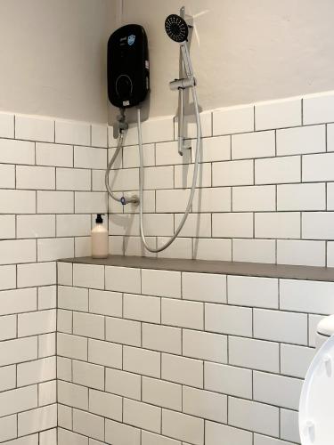 a shower in a white tiled bathroom at Heritage Vacation Inn at Jalan Padungan in Kuching