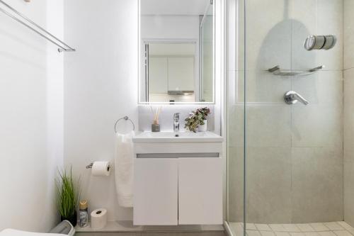 y baño blanco con lavabo y ducha. en *One On Albert 511*Studio Apartment - Swimming Pool, WI-FI & Netflix*, en Ciudad del Cabo