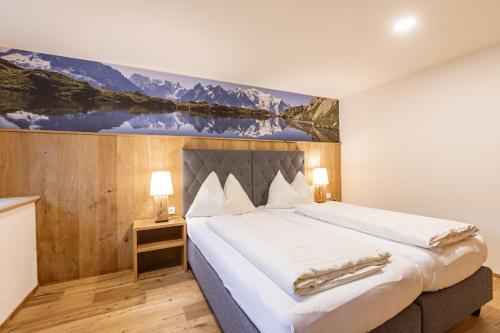 a bedroom with a large bed with a painting on the wall at Vitalhof am Kreischberg by ALPS RESORTS in Bodendorf