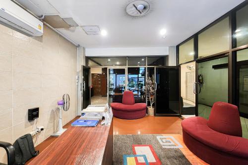 a living room with two red chairs and a clock at Cordia Residence Sathorn in Bang Rak
