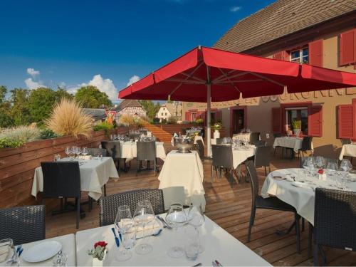 un restaurant avec des tables, des chaises et un parasol rouge dans l'établissement Suite Or avec Sauna Privatif et Cuisine Équipée - Idéale pour un Séjour Relaxant en Alsace - FR-1-744-13, à Wittersdorf