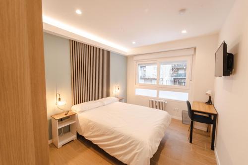 1 dormitorio con cama, escritorio y ventana en I'M Room Suites Nuevos Ministerios - Bernabeu 'Digital Access', en Madrid