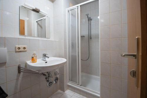 ein weißes Bad mit einem Waschbecken und einer Dusche in der Unterkunft Moderne Einraumwohnung in Leipzig in Leipzig