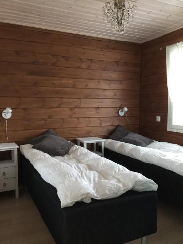 two beds in a room with wooden walls at Nellim Holiday Home, Sámi Village in Nellimö