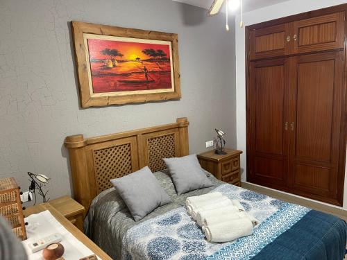 una camera da letto con un letto e un dipinto sul muro di Casa Bornes a Sanlúcar de Barrameda