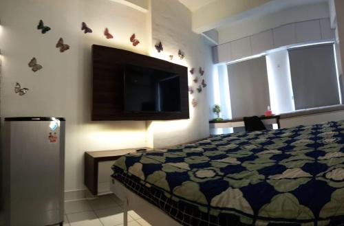 a bedroom with a bed and a flat screen tv at Capital O 93490 Yubi Room Patraland in Bekasi