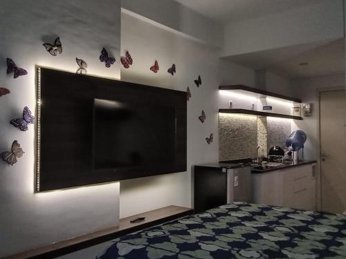 a bedroom with a large flat screen tv and butterflies on the wall at Capital O 93490 Yubi Room Patraland in Bekasi