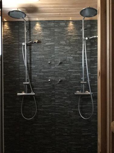 a shower with two hoses in a black wall at Nellim Holiday Home, Sámi Village in Nellimö