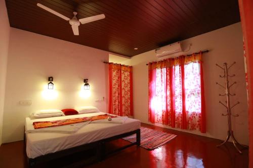 Schlafzimmer mit einem Bett und einem Fenster mit roten Vorhängen in der Unterkunft Marari John Villa in Mararikulam
