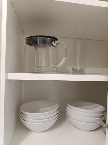 two white plates and bowls on a shelf in a kitchen at Amaprament Do Poznania self check-in 24h, free parking in Poznań