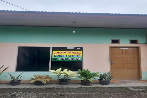 a building with potted plants in front of a door at Hotel O Kamboja Homestay Syariah in Delitua