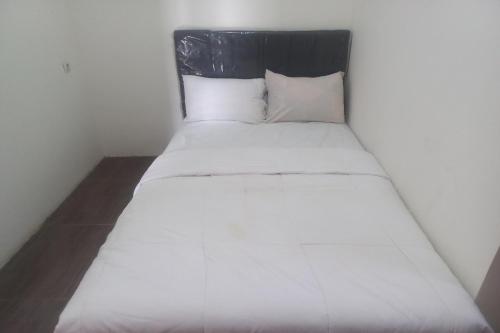uma cama branca com uma cabeceira preta e almofadas brancas em OYO 93505 Harvest Inn Syariah em Purwokerto