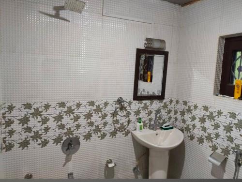 a white bathroom with a sink and a mirror at Country side cottage in Gulmarg