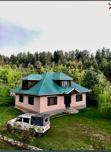 a house with a green roof and a van in front of it at Country side cottage in Gulmarg
