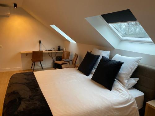 1 dormitorio con cama con almohadas y ventana en 't pure genot, en Dilsen-Stokkem
