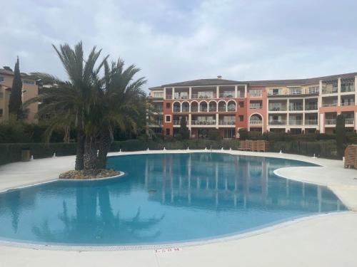 a large swimming pool with a palm tree in front of a building at Vacances, thalasso, télétravail dans superbe T3 mer à 100 m, centre à 400 m in Les Issambres