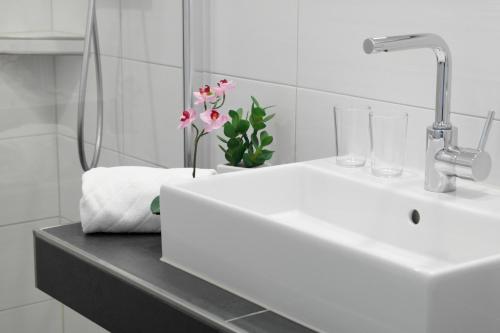 a bathroom with a sink and a vase of flowers at Hotel Blauer Fasan in Wiesmoor