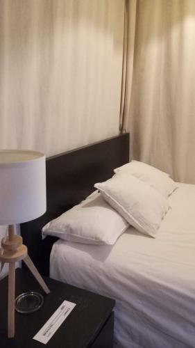a bed with white pillows and a table with a lamp at Habitación en casco histórico in Seville