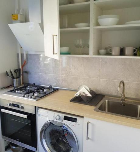uma cozinha com uma máquina de lavar roupa e um lavatório em Modern studio apartment Baltijos em Klaipėda