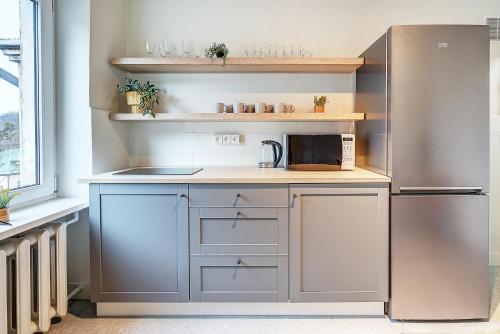 a kitchen with a stainless steel refrigerator and white cabinets at Funky Penthouse City Center in Kaunas