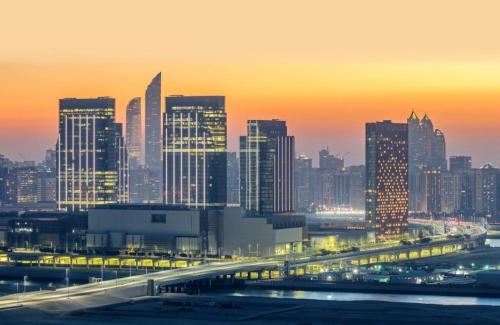 a city skyline at night with a bridge and buildings at MBZ - Pleasant Tidy Room in Abu Dhabi