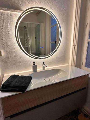 La salle de bains est pourvue d'un lavabo blanc et d'un miroir. dans l'établissement Appartement de charme Les Orfèvres, à Moulins