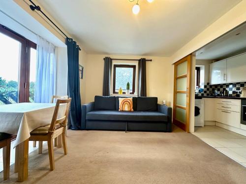 a living room with a blue couch and a kitchen at Super Apartment next to Bicester Village Sleeps 4 in Bicester